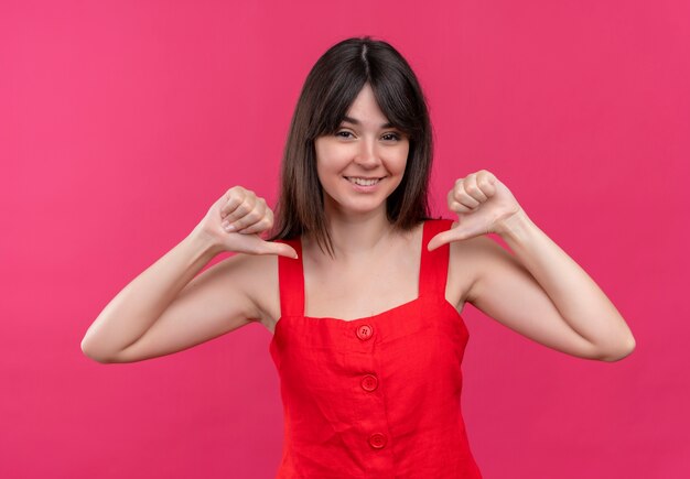 Smiling young caucasian girl points herself with both hands on isolated pink background