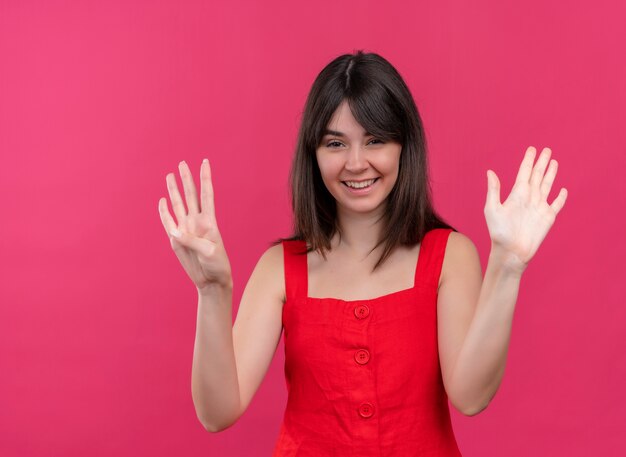 Smiling young caucasian girl showing nine with fingers and looking at cameraon isolated pink background
