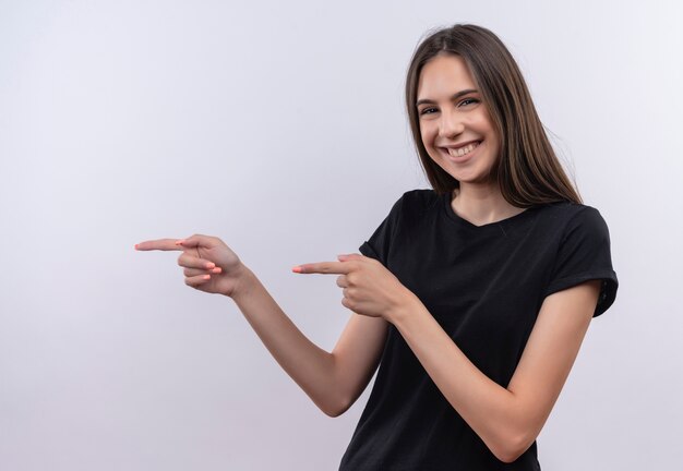 Smiling young caucasian girl wearing black t-shirt point fingers to side on isolated white background