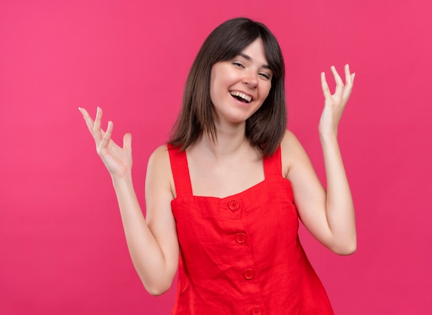 Smiling young caucasian girl with raised empty hands on isolated pink background