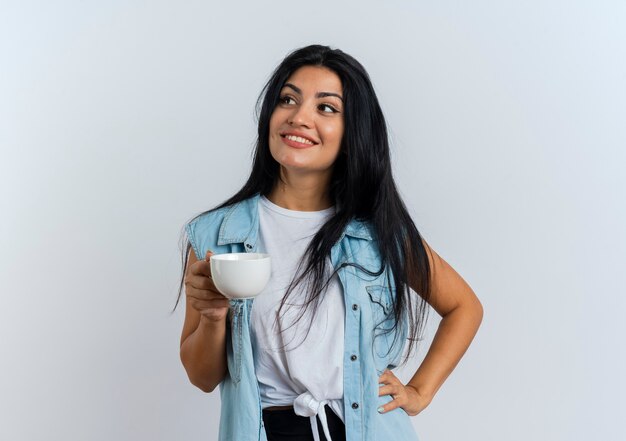 Smiling young caucasian woman holds cup looking at side