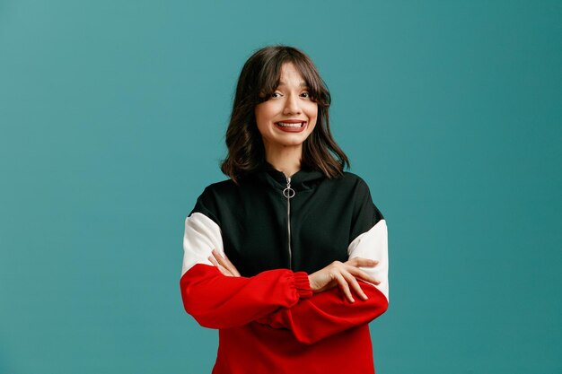Smiling young caucasian woman keeping arms crossed looking at camera isolated on blue background