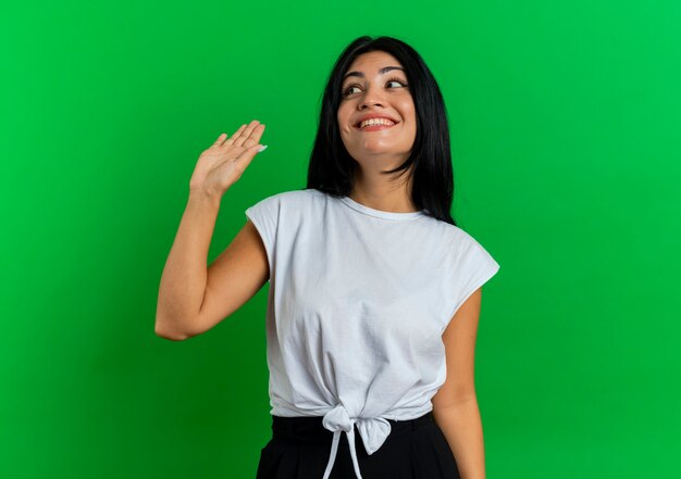 Free photo smiling young caucasian woman stands with raised hand looking at side