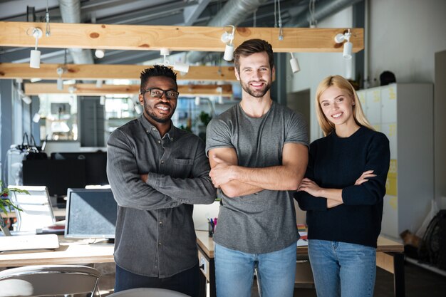 Smiling young colleagues standing with arms crossed