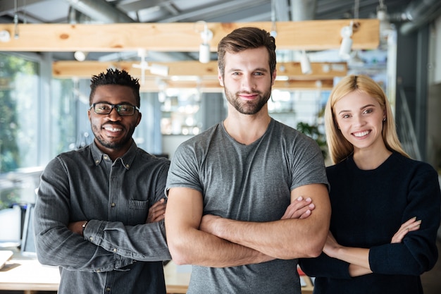 Smiling young colleagues standing with arms crossed