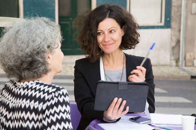 Free photo smiling young consultant offering pen to elderly client