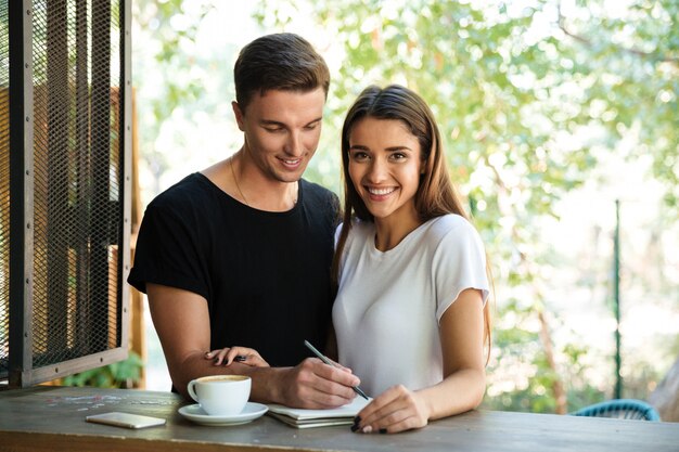 Smiling young couple making notes in a textbook together