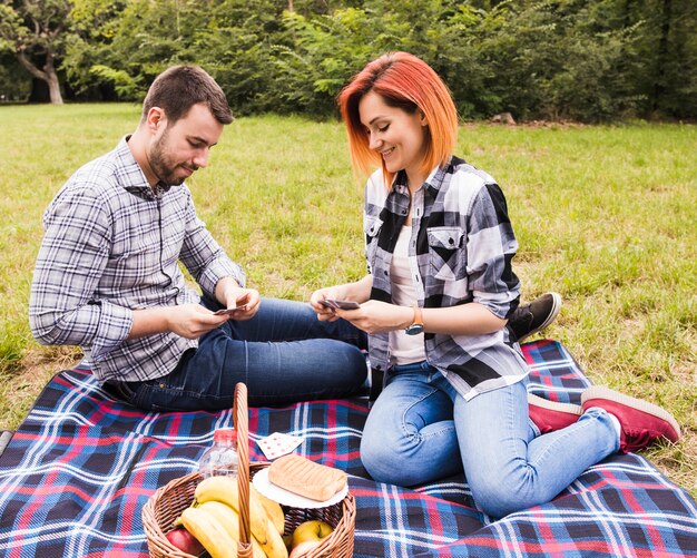 Smiling young couple playing cards on picnic in the park