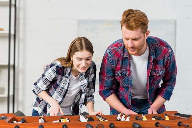 Free photo smiling young couple playing the indoor soccer game at home