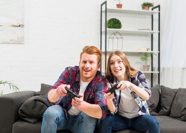 Улыбающаяся молодая пара играет в видеоигру с джойстиком