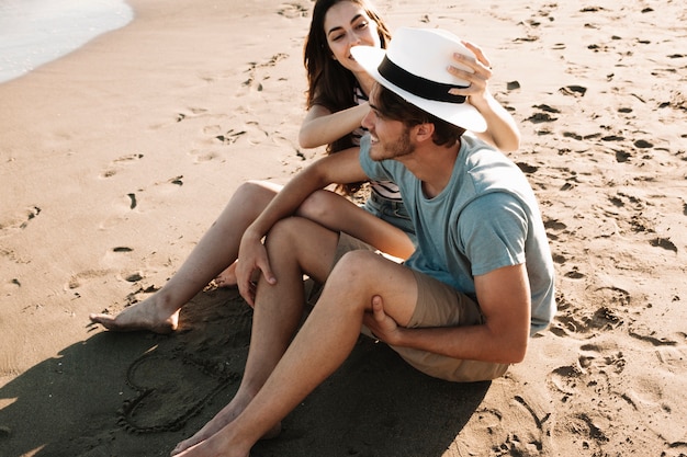 Smiling young couple sitting next to the sea