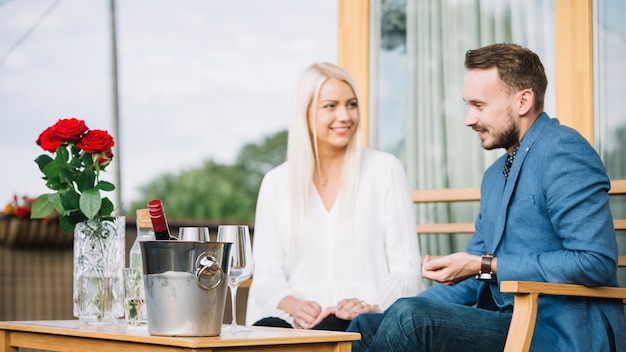 Smiling young couple sitting together with ice bucket on table