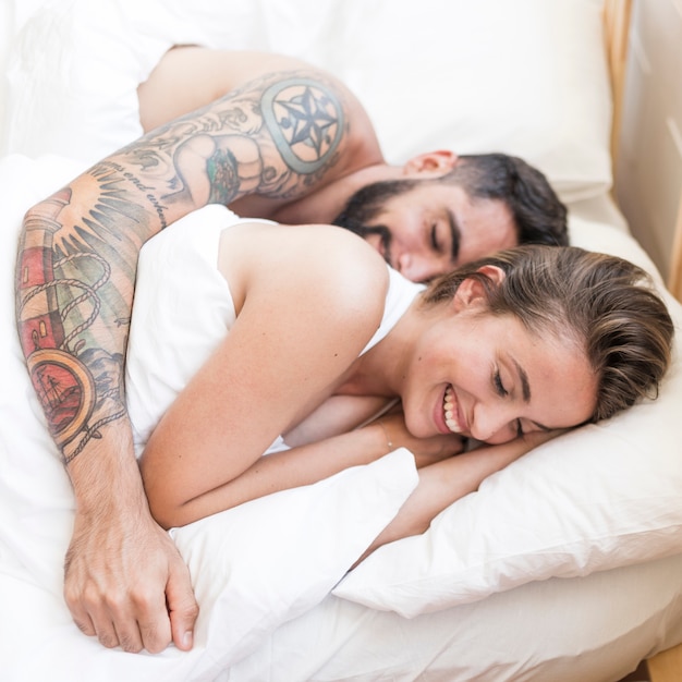 Smiling young couple sleeping together on bed