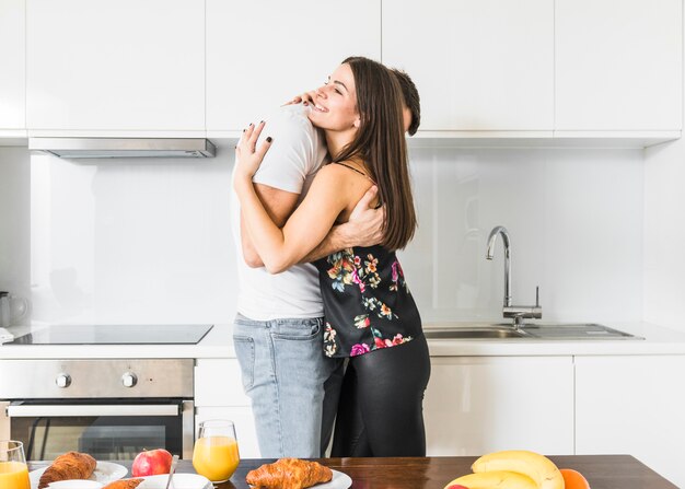 Smiling young couple standing in kitchen embracing