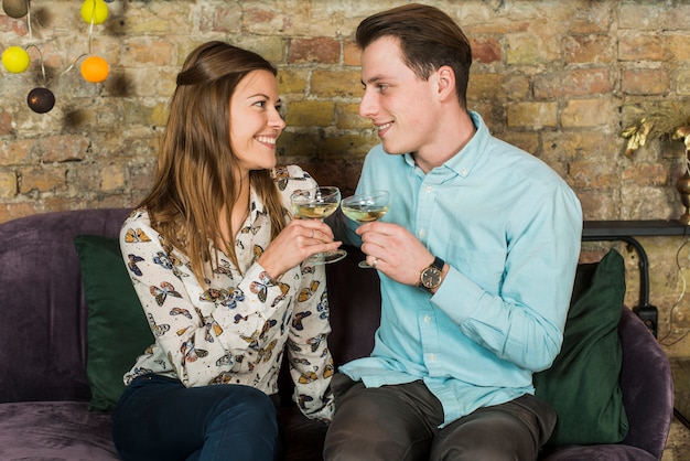 Smiling young couple toasting wine glasses in club