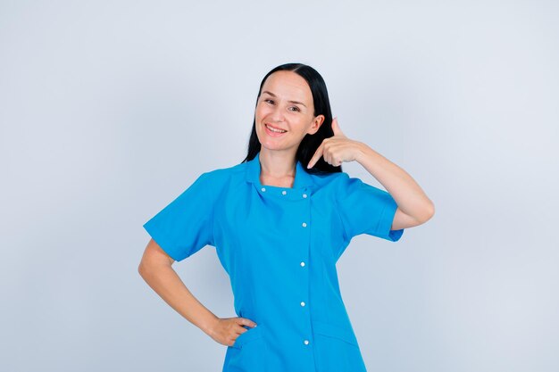 Smiling young doctor is pointing herself with forefinger on white background