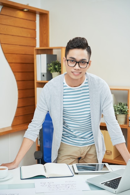 Smiling young ethnic worker at table