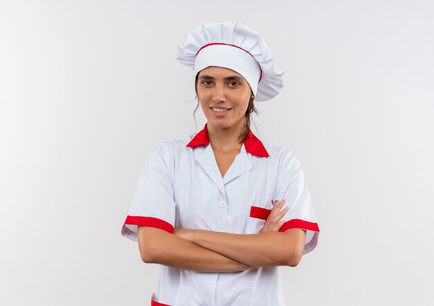 コピースペースと手を交差させるシェフの制服を着て笑顔の若い女性料理人