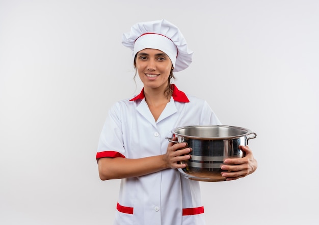 Улыбающаяся молодая женщина-повар в униформе шеф-повара держит кастрюлю с копией пространства