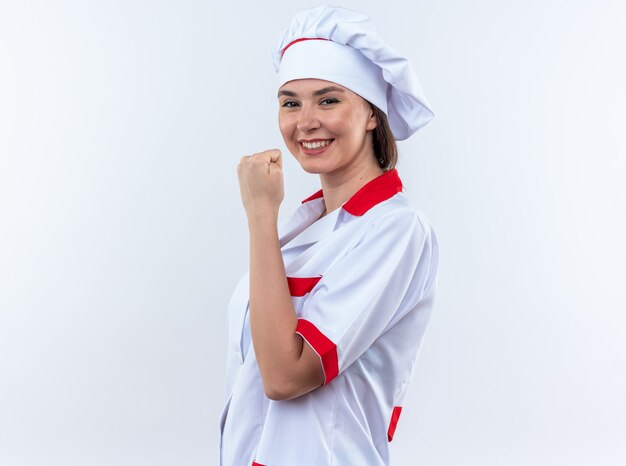흰색 배경에 고립 예 제스처를 보여주는 요리사 유니폼을 입고 웃는 젊은 여성 요리사