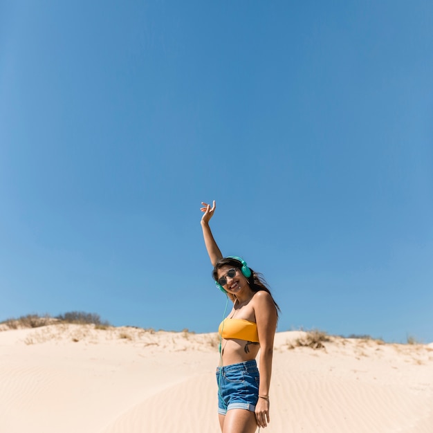 Smiling young female in headphones on beach