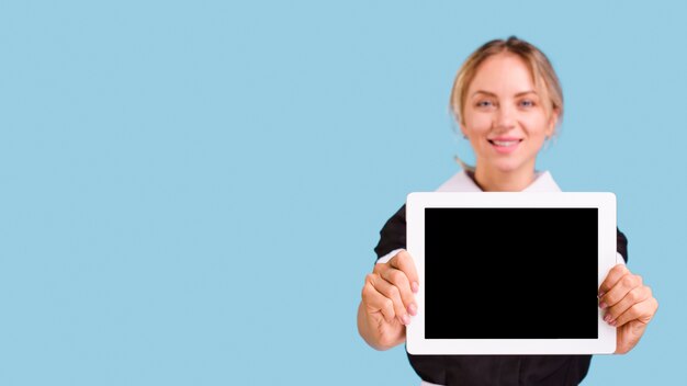 파란색 배경에 디지털 태블릿을 들고 웃는 젊은 여성 관리인
