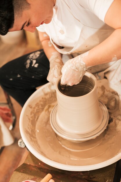 Smiling young female modeling clay on a potter's wheel