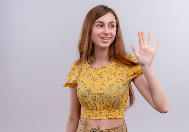 Smiling young girl doing bye gesture on isolated white wall with copy space