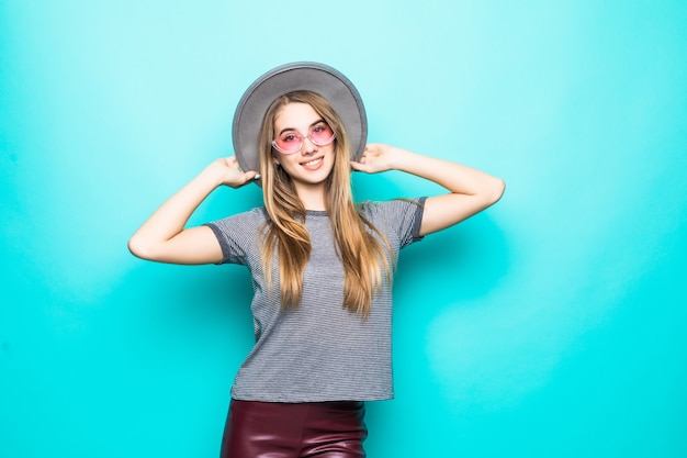 Smiling young girl in fashion t-shirt, hat and transperent glasses isolated on green background