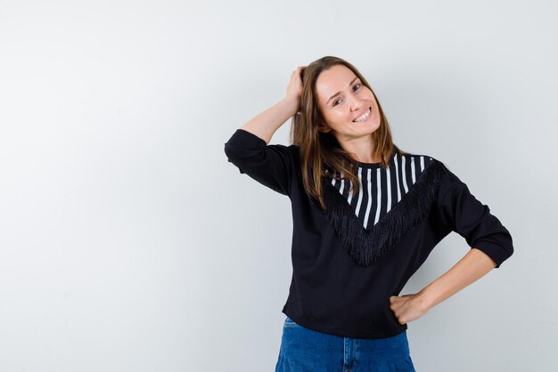 Smiling young girl holding her left hand behind her head on white background