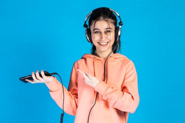 Smiling young girl holding phone and wearing headphones