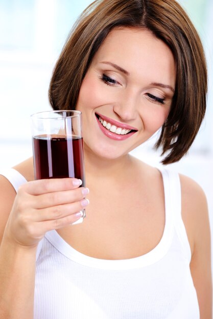 smiling young girl holds a glass of pomegranate  juice