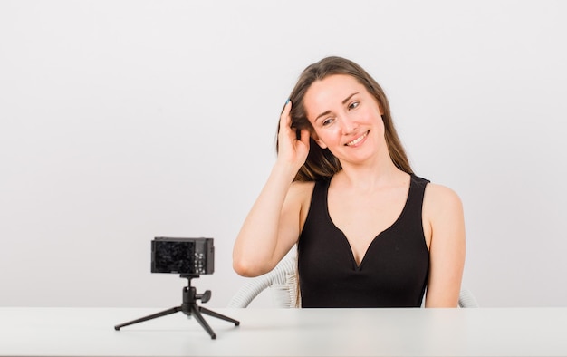 Smiling young girl is looking at camera by holding hair on white background