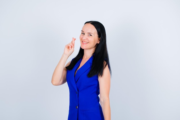 Smiling young girl is showing her crossed fingers on white background