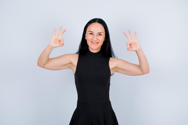 Smiling young girl is showing okay gestures on white background