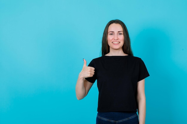 Smiling young girl is showing perfect gesture on blue background