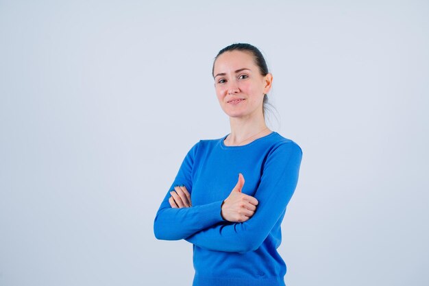 Smiling young girl is showing perfect gesture by crossing arms on white background