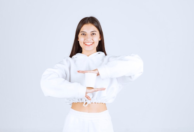 Modello sorridente della ragazza che tiene un bicchiere di plastica.