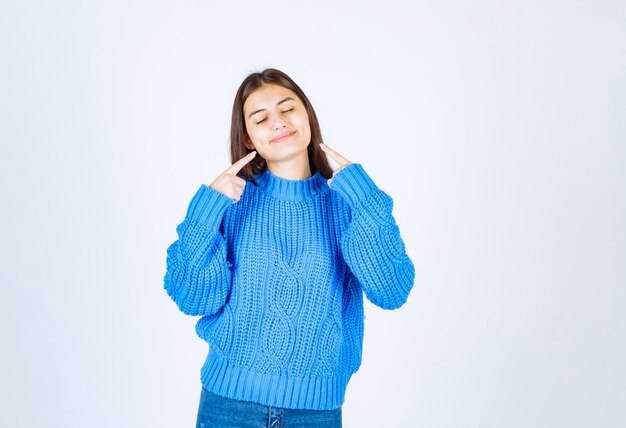 smiling young girl model pointing at her cheeks.