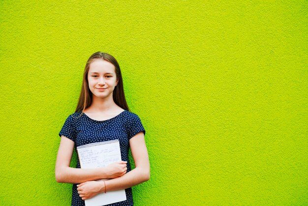 Smiling young girl posing with notepad