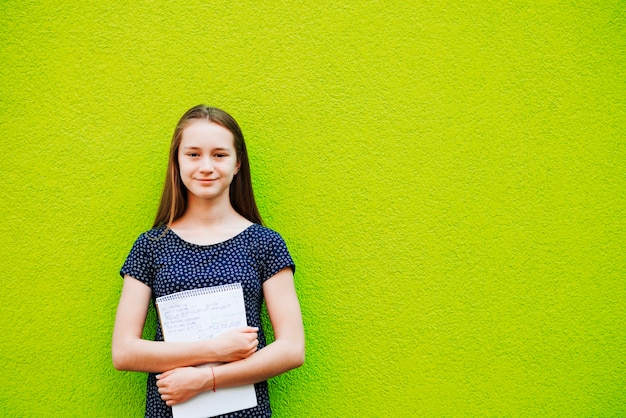 Smiling young girl posing with notepad