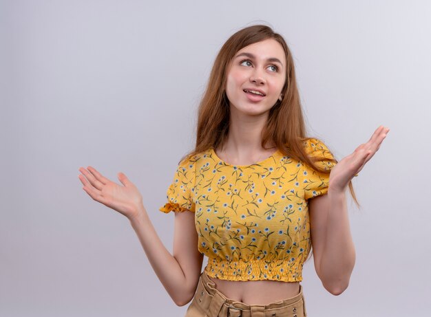 Smiling young girl showing empty hands on isolated white wall