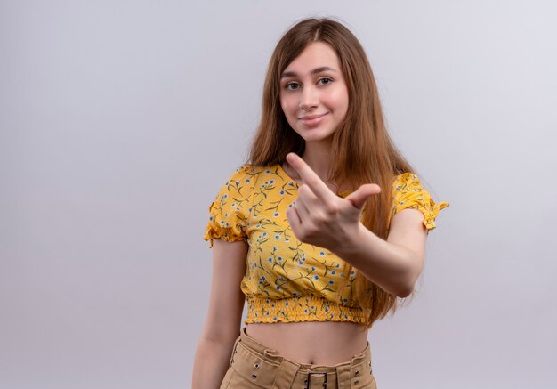 Smiling young girl stretching finger  on isolated white wall with copy space