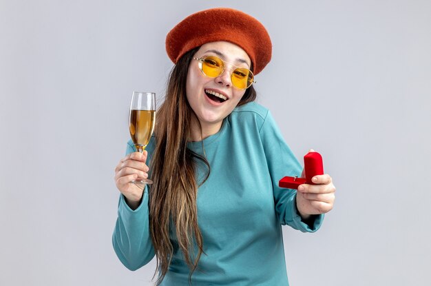 Улыбающаяся молодая девушка в день святого валентина в шляпе с бокалами и бокалом шампанского с обручальным кольцом на белом фоне