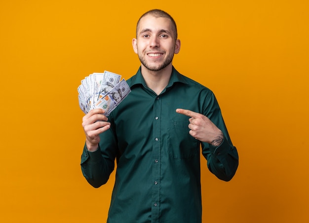 Free photo smiling young handsome guy wearing green shirt holding and points at cash