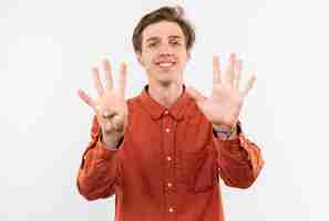 Free photo smiling young handsome guy wearing red shirt showing differents numbers