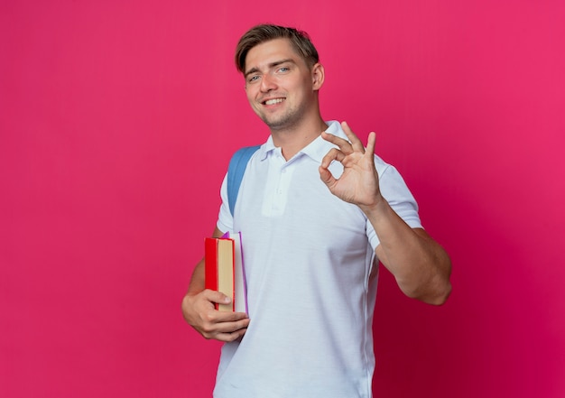 Smiling young handsome male student wearing back bag holding books