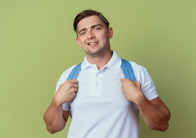 Smiling young handsome male student wearing back bag isolated on olive green