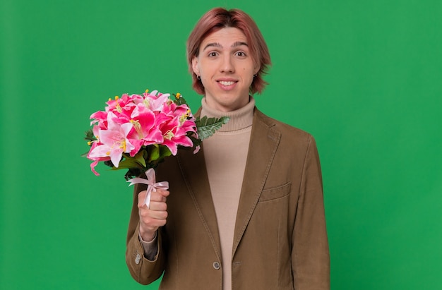 花の花束を保持している若いハンサムな男の笑顔