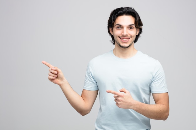 smiling young handsome man looking at camera pointing to side isolated on white background